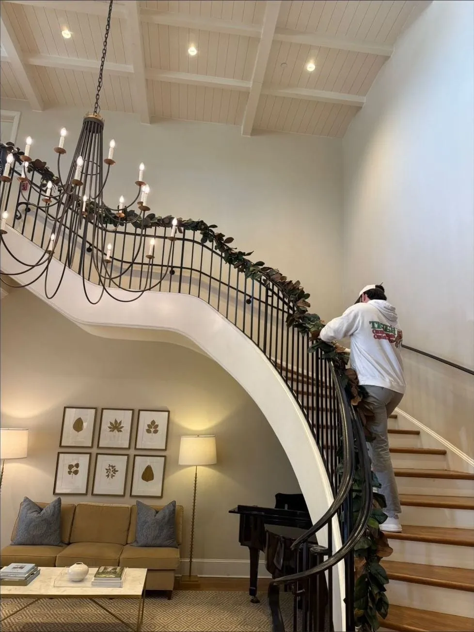 Hanging magnolia garland along a curved staircase railing