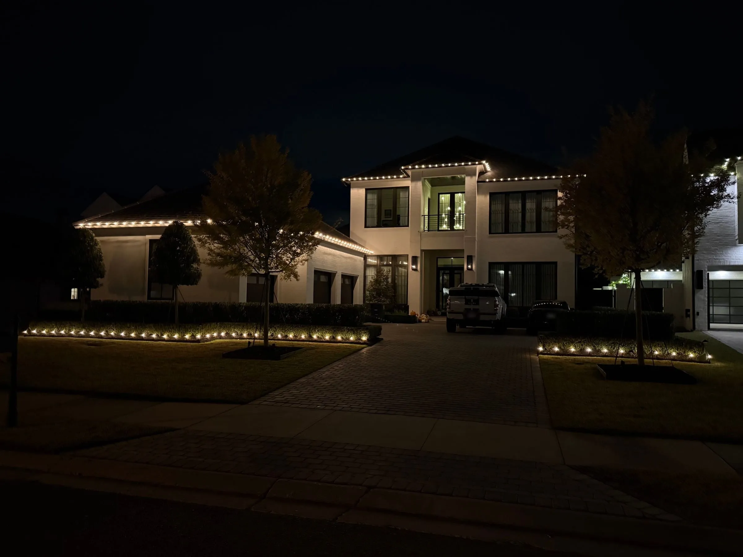 Modern white two-story with roofline and ground lights
