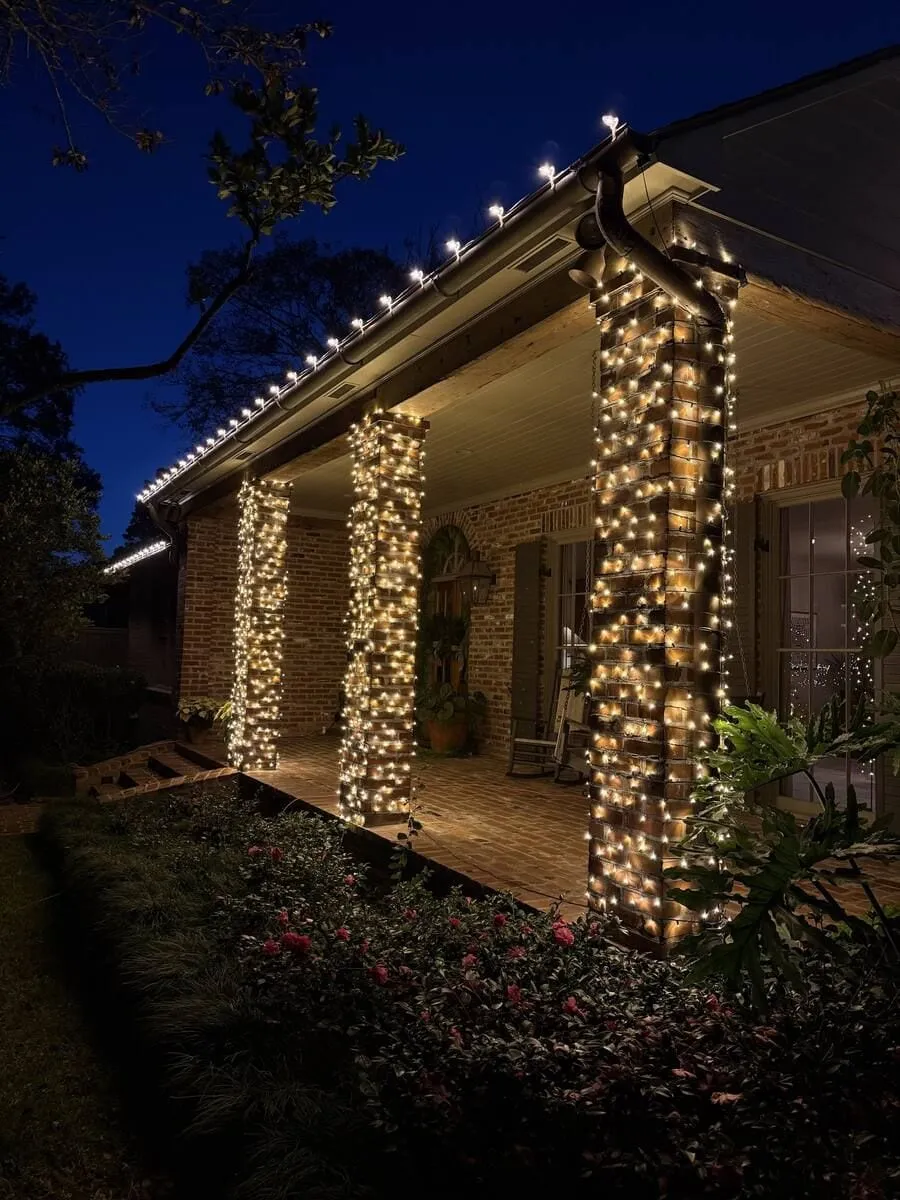 Brick porch columns wrapped top to bottom in warm white lights