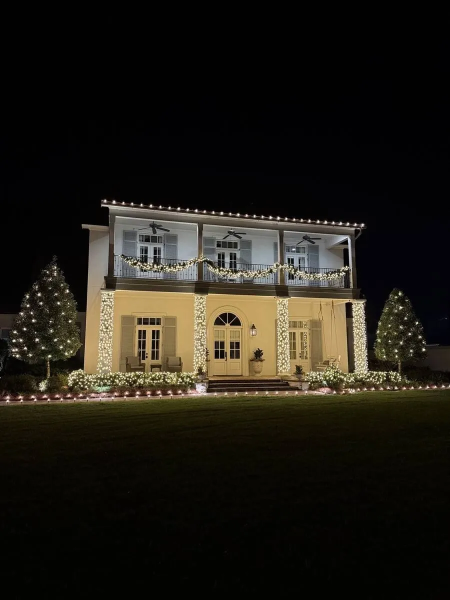 Two-story raised house with lit roofline, column wraps and garland